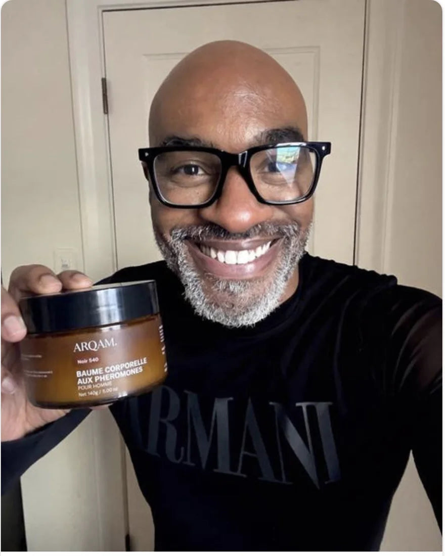 Client ARQAM souriant, lunettes noires, le pot NOIR 540 à la main