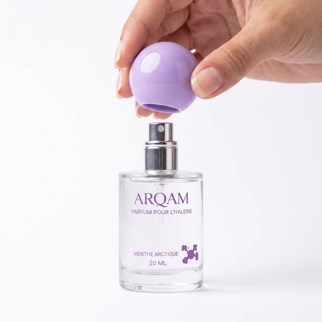 Une main f&eacute;minine soul&egrave;ve le capuchon lilas du flacon ARQAM